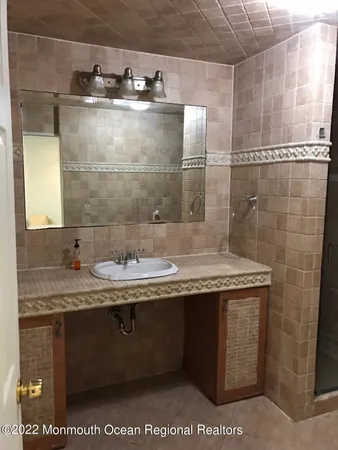 a bathroom with a granite countertop sink a mirror and shower