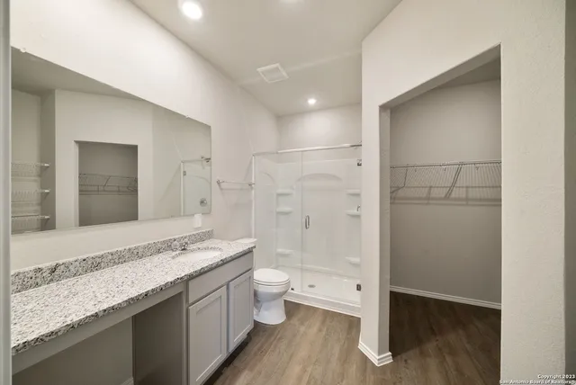 a bathroom with a granite countertop sink a toilet and shower