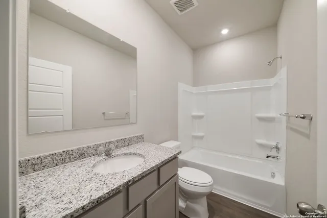 a bathroom with a granite countertop sink a toilet and bathtub