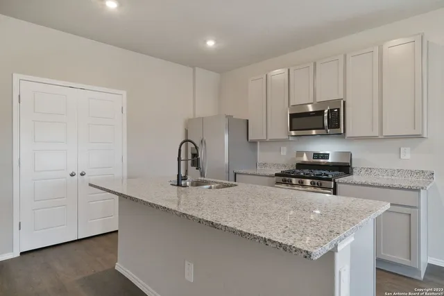 a kitchen with stainless steel appliances granite countertop a sink a stove and a microwave with wooden floor