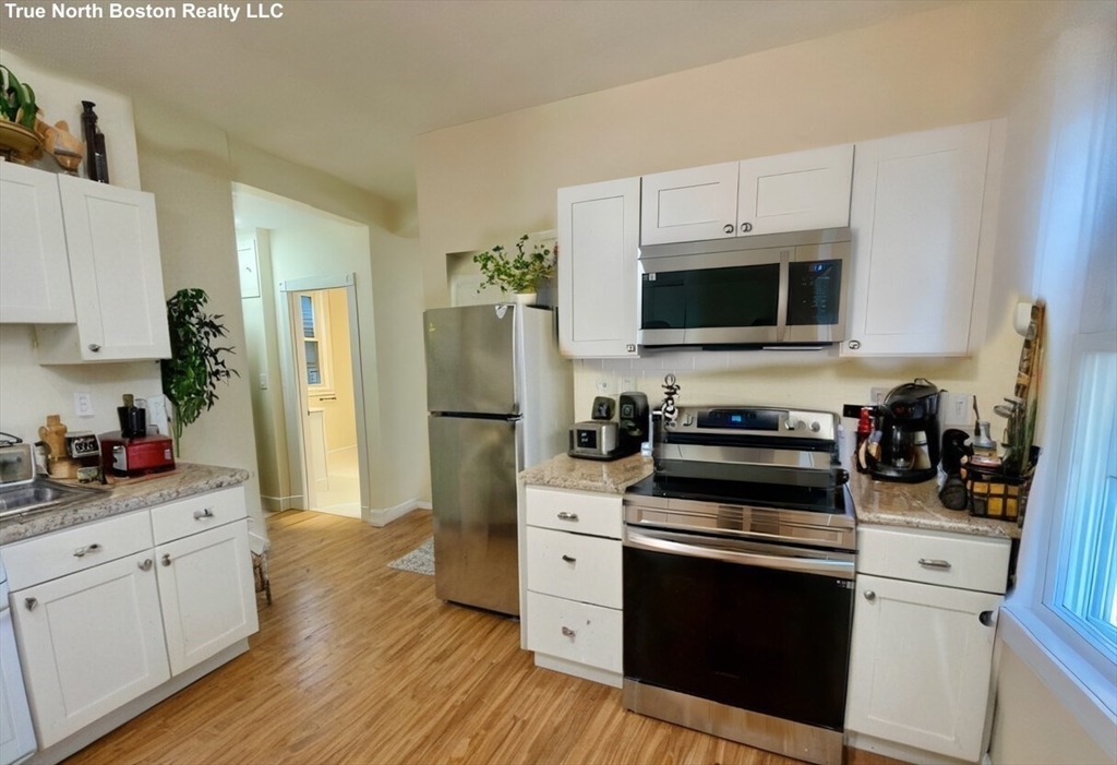 207 Princeton Street, Unit 1 Boston, MA 02128 - Photo 13 of 15 a kitchen with cabinets stainless steel appliances and wooden floor