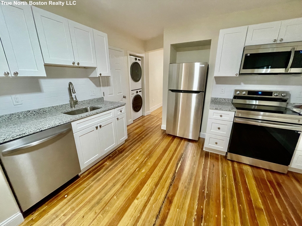 207 Princeton Street, Unit 1 Boston, MA 02128 - Photo 3 of 15 a kitchen with wooden floors and appliances