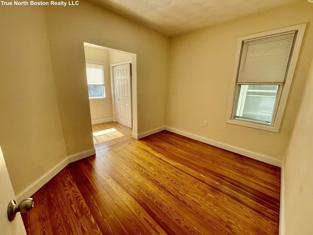 207 Princeton Street, Unit 1 Boston, MA 02128 - Photo 8 of 15 a view of an empty room with wooden floor and a window