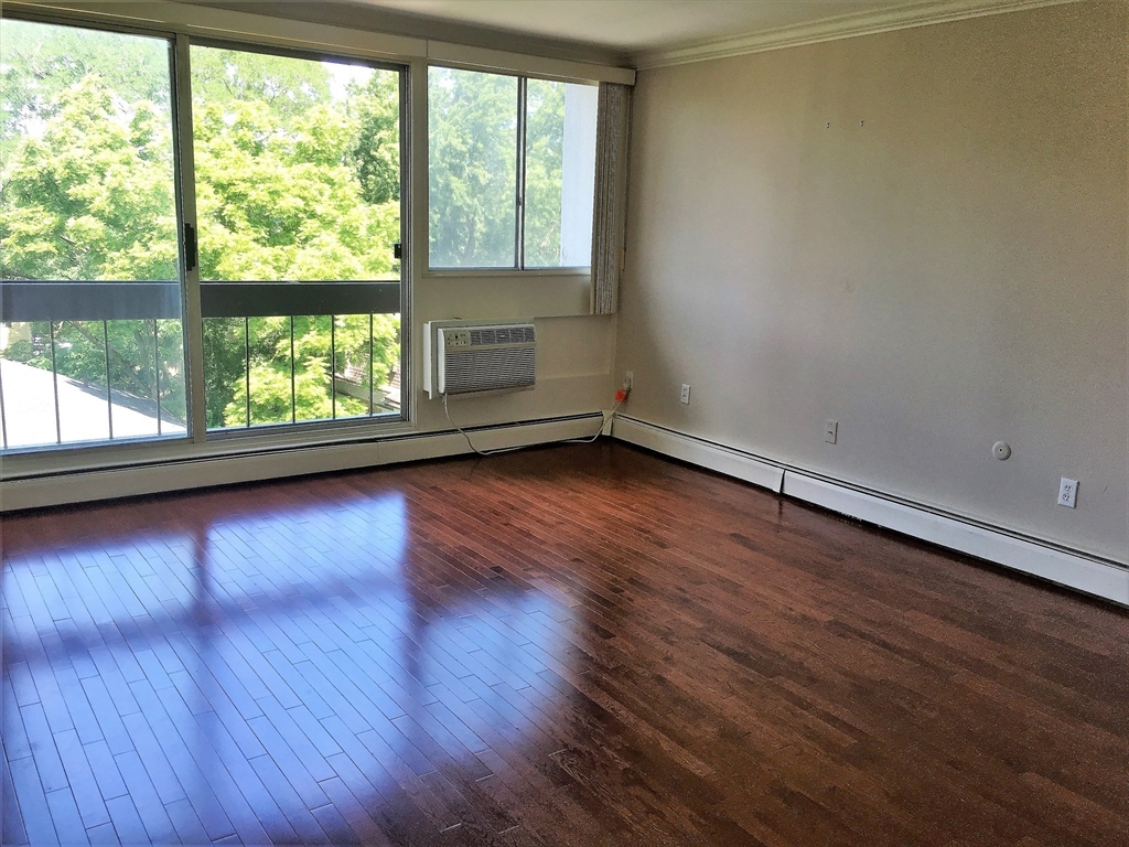12 Inman Street, Unit 52 Cambridge, MA 02139 - Photo 2 of 12 an empty room with wooden floor and windows
