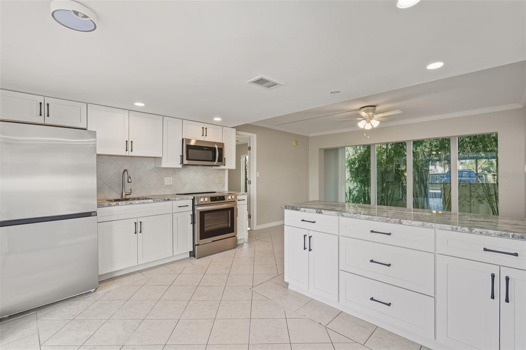 5055 North Beach Road, Unit 106 Englewood, FL 34223 - Photo 4 of 34 a kitchen with granite countertop white cabinets and white stainless steel appliances