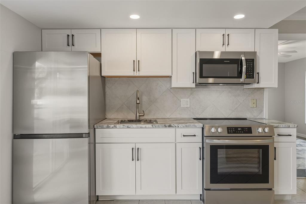 5055 North Beach Road, Unit 106 Englewood, FL 34223 - Photo 6 of 34 a kitchen with stainless steel appliances granite countertop a stove a refrigerator and a microwave