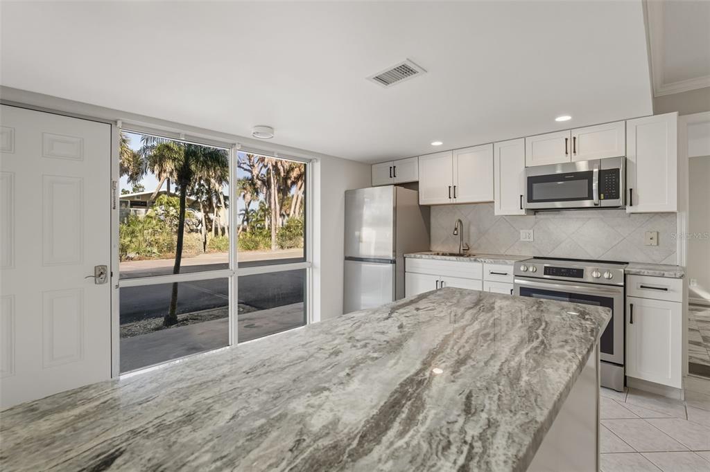 5055 North Beach Road, Unit 106 Englewood, FL 34223 - Photo 8 of 34 a kitchen with stainless steel appliances granite countertop a stove top oven a sink dishwasher a refrigerator and cabinets with wooden floor