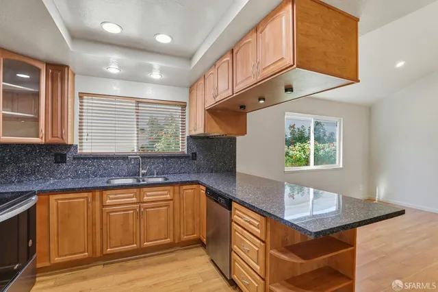 a kitchen with stainless steel appliances granite countertop a refrigerator a sink a stove and a refrigerator