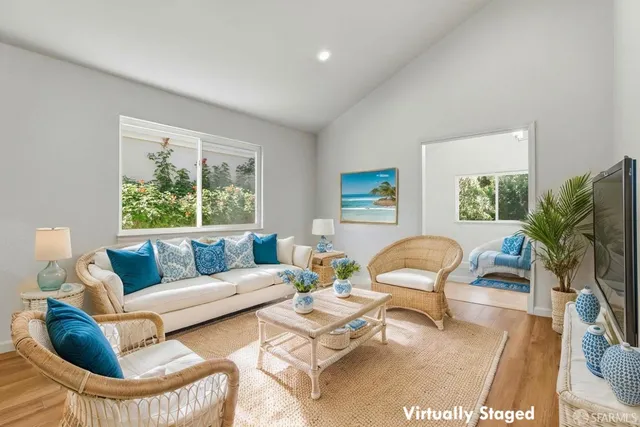 an empty room with wooden floor and way to kitchen
