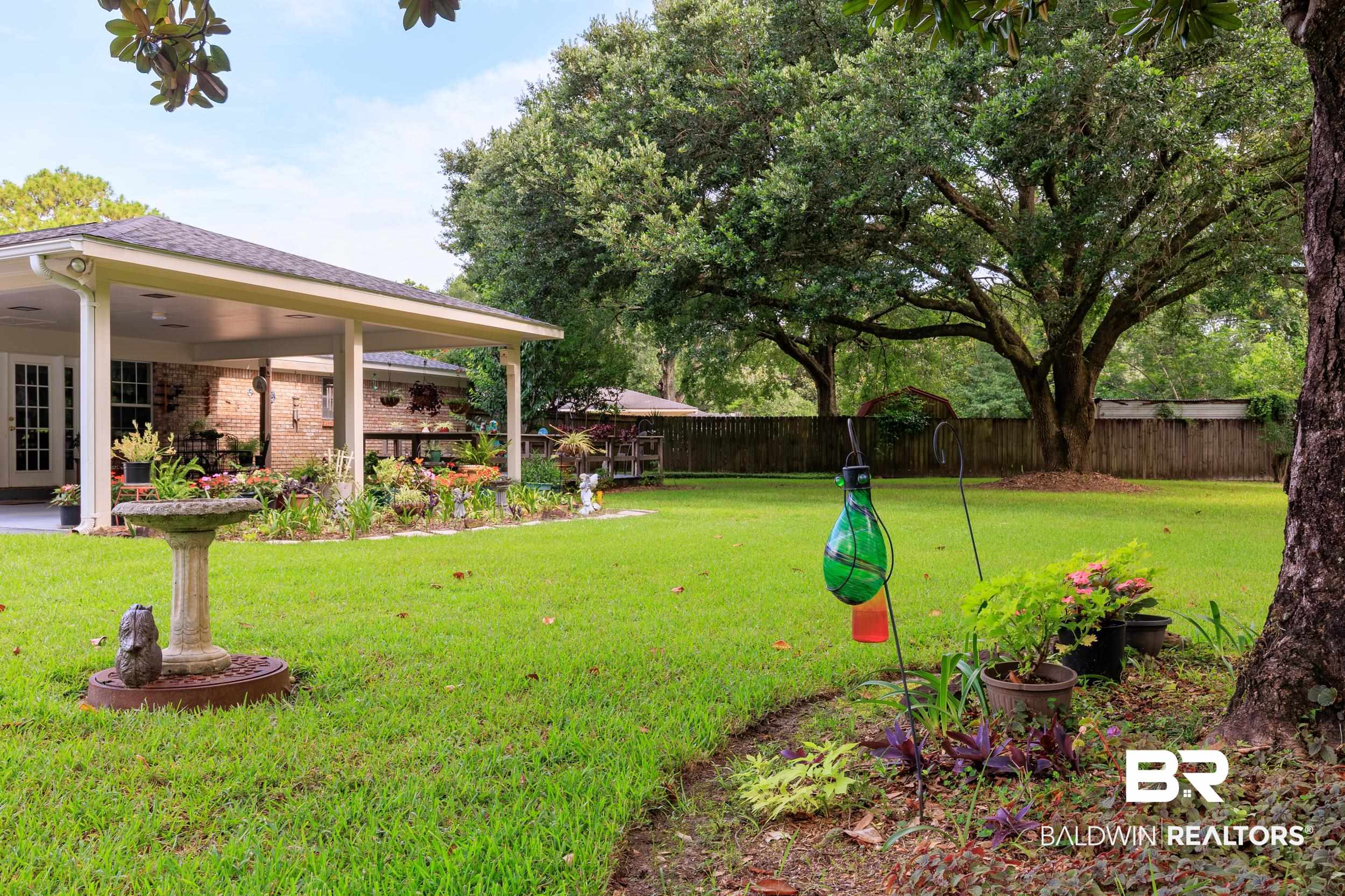 1367 Spring Valley Court Mobile, AL 36693 - Photo 20 of 29 Expansive backyard featuring a manicured lawn, mature trees, and a covered patio with brick siding