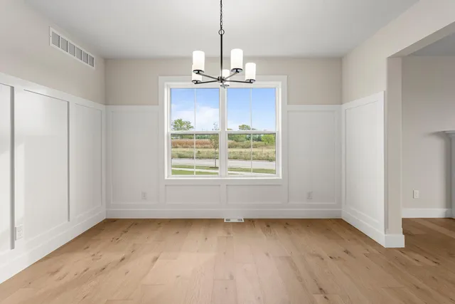 a view of a hallway with wooden floor and a bathroom