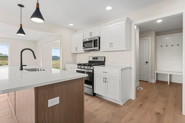 a kitchen with kitchen island granite countertop a stove a sink a center island and a wooden floor