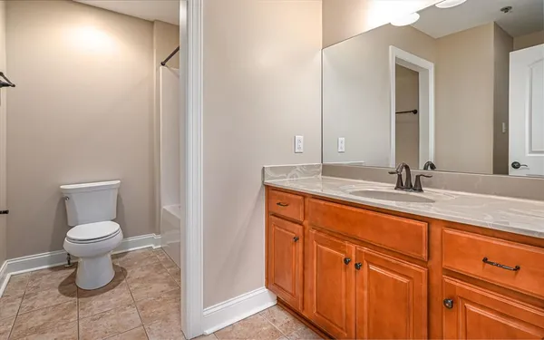 a bathroom with a granite countertop sink toilet and mirror