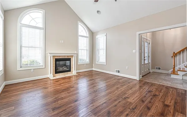 an empty room with wooden floor fireplace and windows