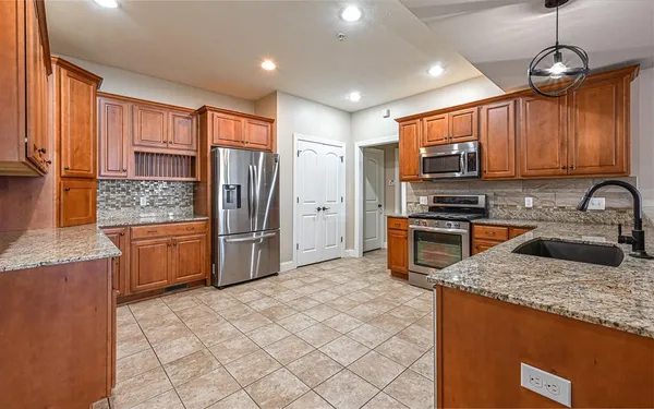a kitchen with stainless steel appliances granite countertop a stove a sink and a refrigerator