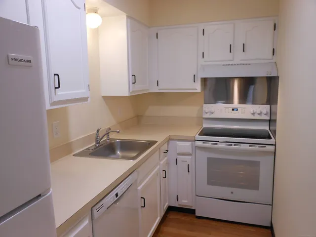 a kitchen with granite countertop white cabinets and white appliances