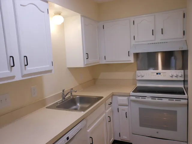 a kitchen with white cabinets and appliances