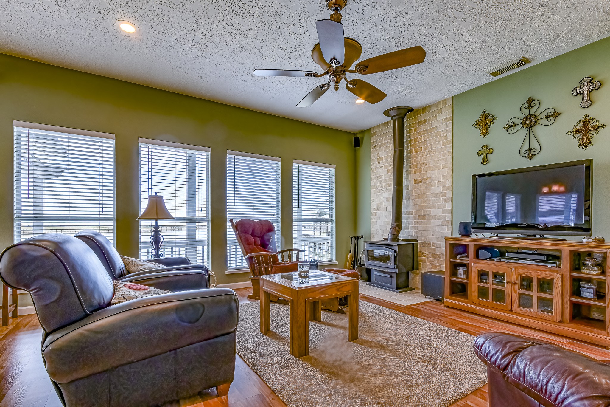 27 Marina Court Coldspring, TX 77331 - Photo 21 of 38 Light-filled living room with expansive windows, warm wood floors, and cozy fireplace.