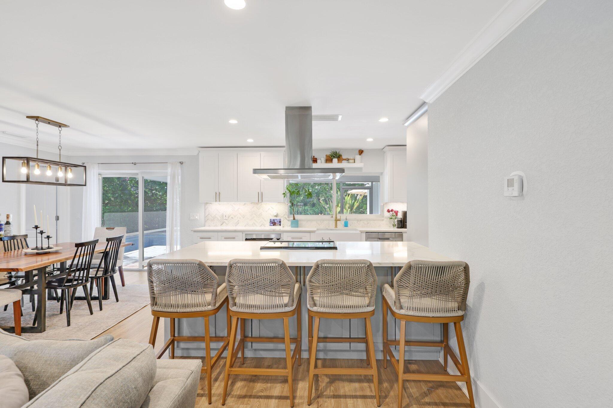 926 Southwest 1st Street Boca Raton, FL 33486 - Photo 18 of 60 a kitchen with a dining table chairs and white cabinets