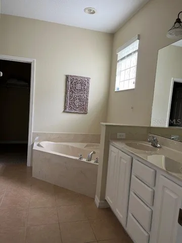 a spacious bathroom with a tub sink and mirror