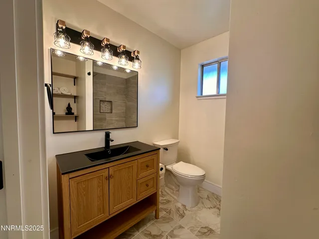 a bathroom with a granite countertop sink a toilet a mirror and shower
