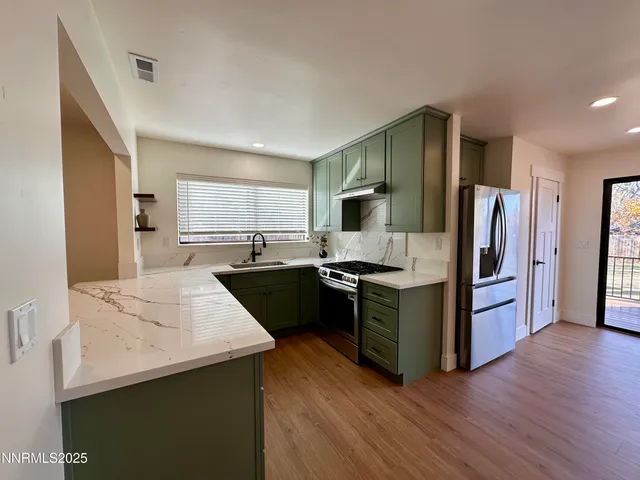 a kitchen with stainless steel appliances kitchen island granite countertop a refrigerator stove and sink