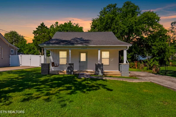 a house view with a sitting space garden view with a large tree