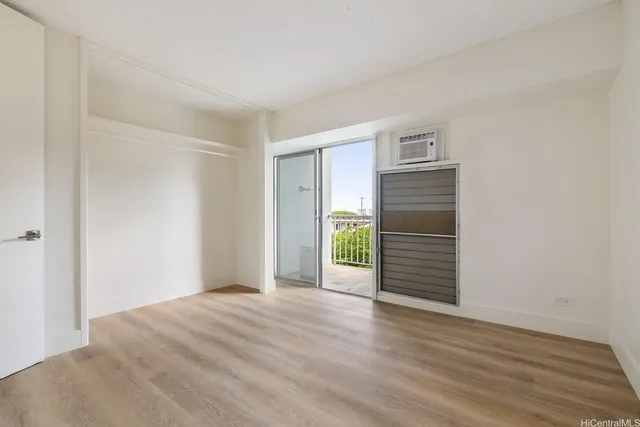 a view of an empty room with wooden floor and closet