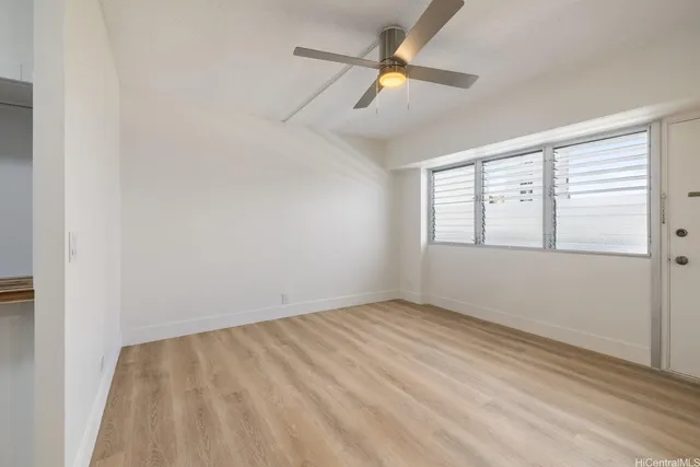 an empty room with windows and fan