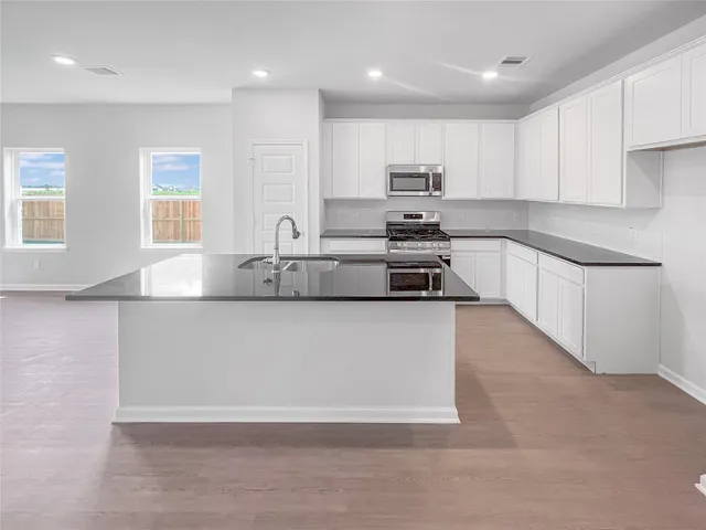 a large kitchen with stainless steel appliances granite countertop a stove a sink and a granite counter tops