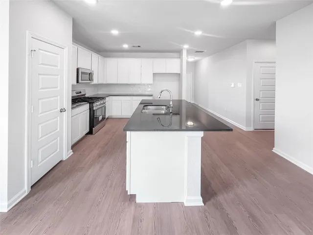 a kitchen with granite countertop a sink and wooden floors