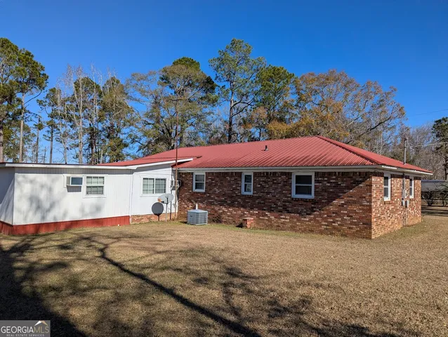 a backyard of a house with large trees and covered with snow in the background