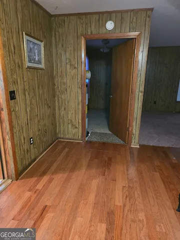 a view of a hallway with wooden floor and a bathroom