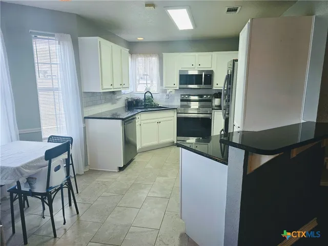a kitchen with stainless steel appliances granite countertop a refrigerator sink and stove