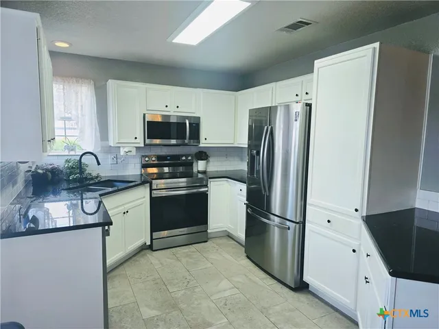 a kitchen with granite countertop a refrigerator and a sink
