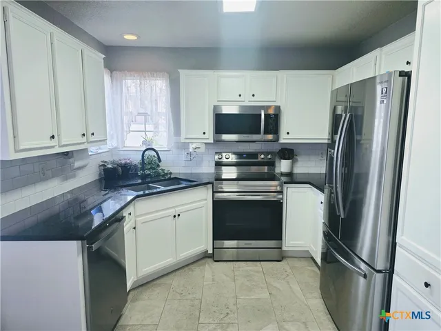 a kitchen with stainless steel appliances granite countertop a refrigerator stove top oven and sink