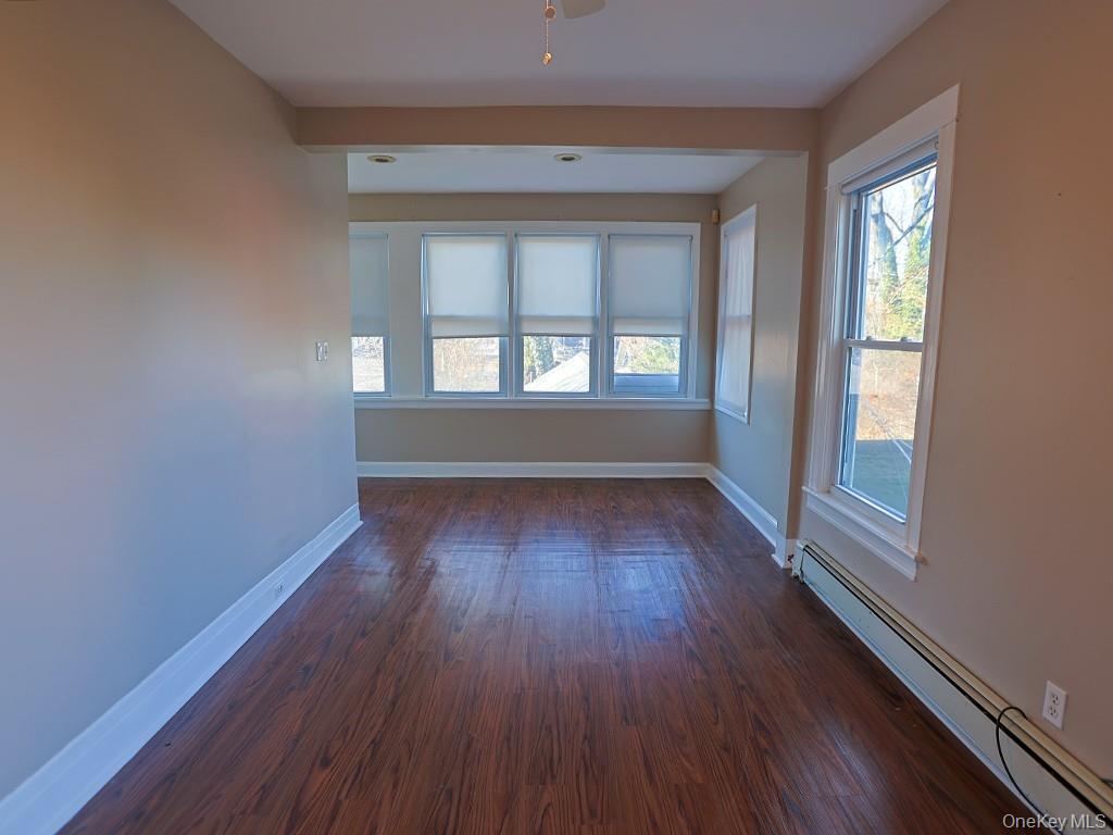 113 Hooker Avenue Poughkeepsie, NY 12601 - Photo 13 of 49 Empty room with a baseboard heating unit, healthy amount of natural light, and dark wood-style flooring