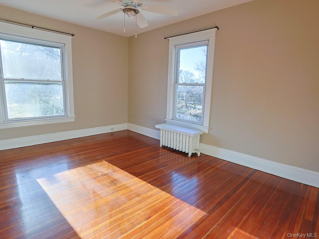 113 Hooker Avenue Poughkeepsie, NY 12601 - Photo 17 of 49 Empty room featuring dark wood finished floors, radiator, and a ceiling fan