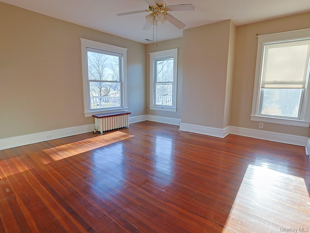 113 Hooker Avenue Poughkeepsie, NY 12601 - Photo 18 of 49 Unfurnished room featuring hardwood / wood-style floors, radiator heating unit, and a ceiling fan