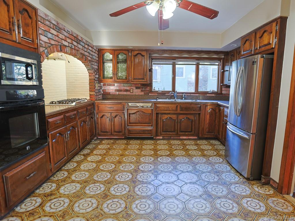 113 Hooker Avenue Poughkeepsie, NY 12601 - Photo 6 of 49 Kitchen with appliances with stainless steel finishes, ceiling fan, glass insert cabinets, light floors, and brown cabinets