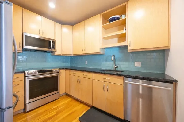 a kitchen with stainless steel appliances granite countertop a sink a microwave cabinets and a wooden floor