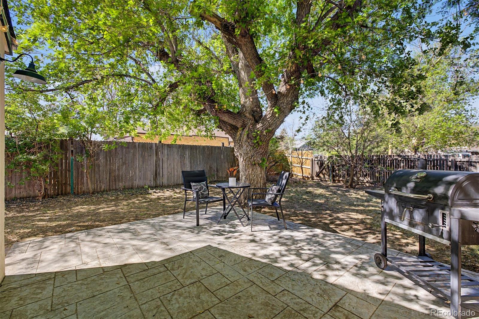 6790 West 48th Avenue Wheat Ridge, CO 80033 - Photo 26 of 30 a backyard with table and chairs with wooden fence and plants