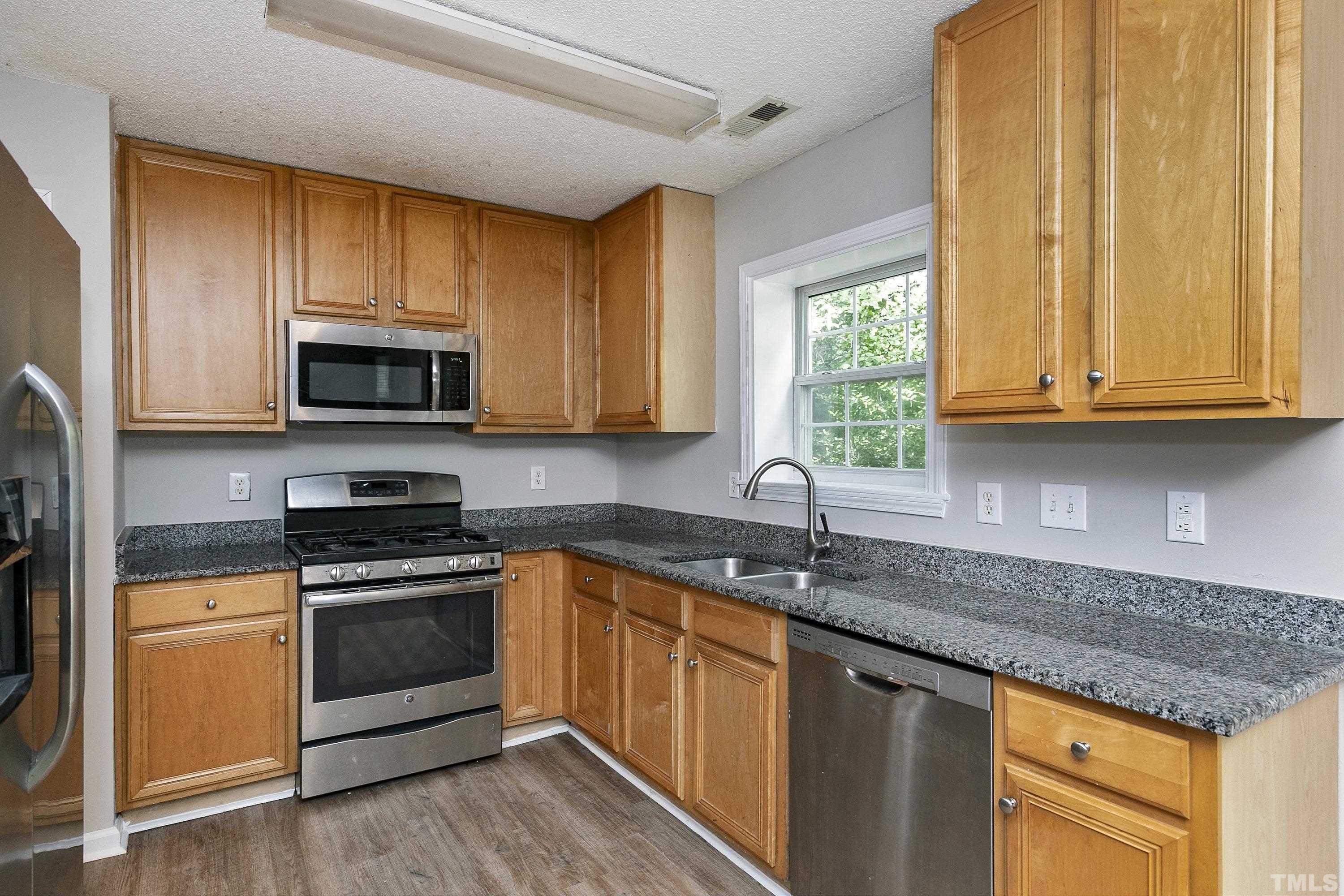 613 Branchview Drive Durham, NC 27713 - Photo 10 of 40 a kitchen with granite countertop a sink stainless steel appliances wooden cabinets and a window