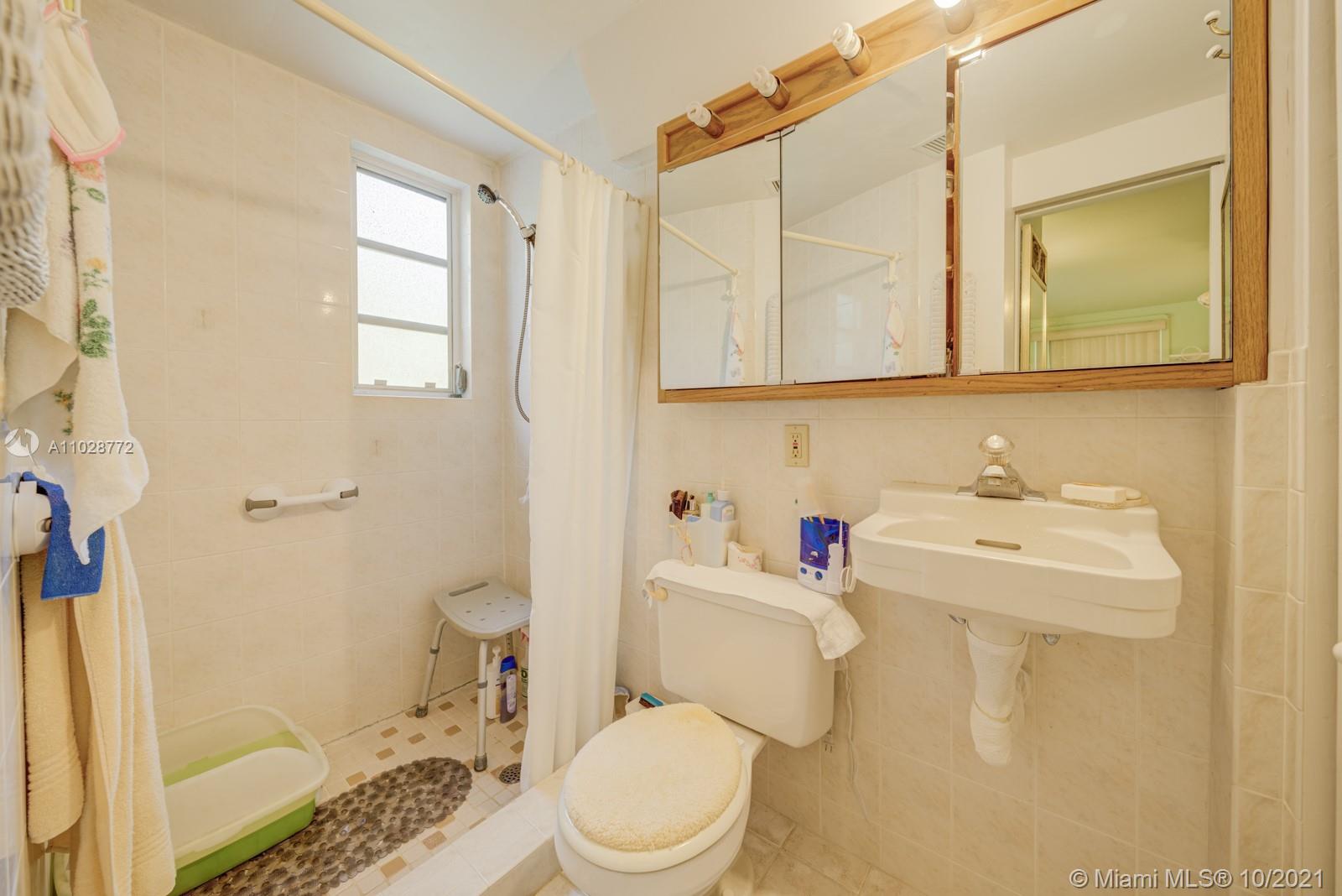 477 Northeast 154th Street Miami, FL 33162 - Photo 11 of 26 a bathroom with a sink a toilet and shower curtain
