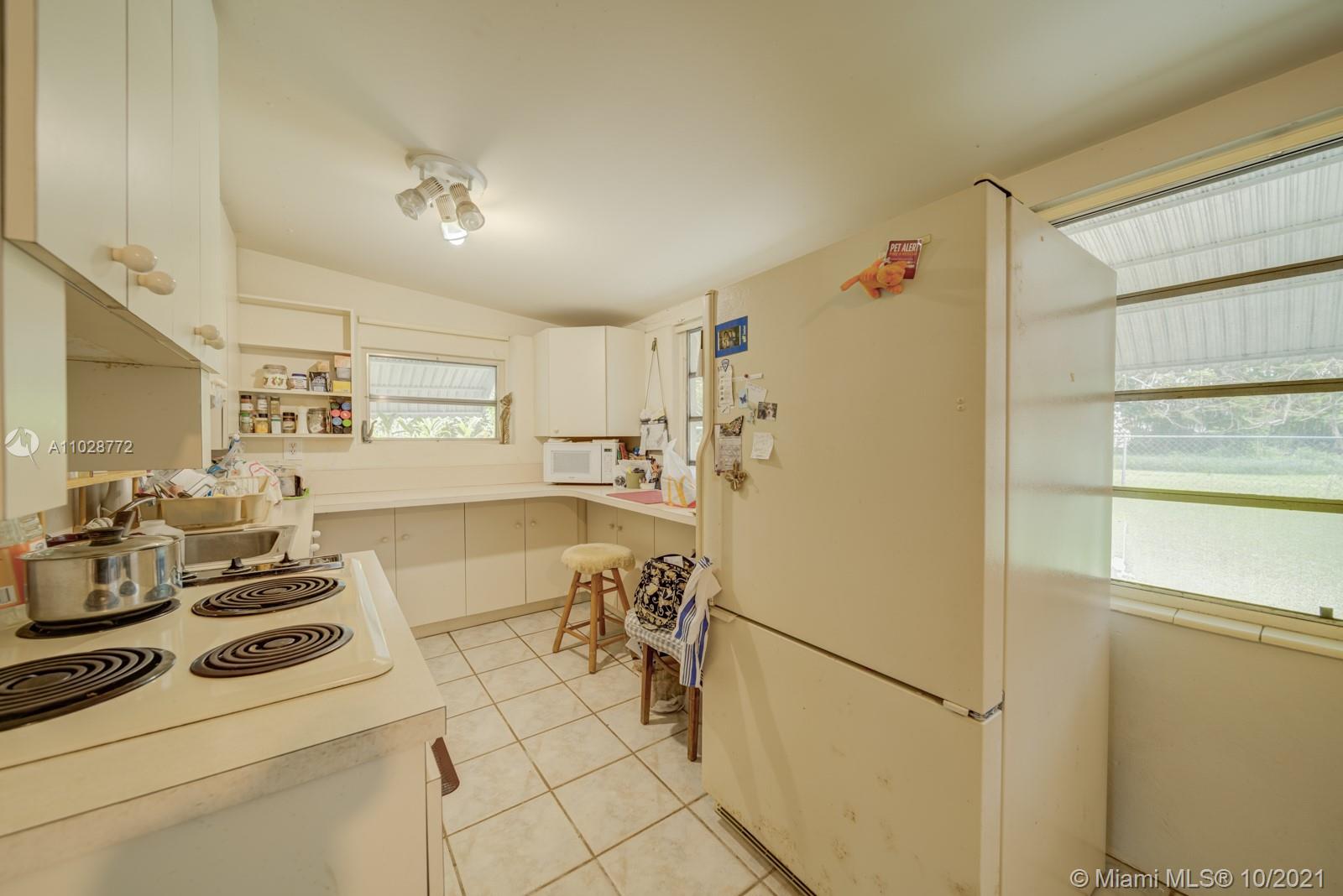 477 Northeast 154th Street Miami, FL 33162 - Photo 24 of 26 a kitchen with a refrigerator a stove a cabinets and a dining table