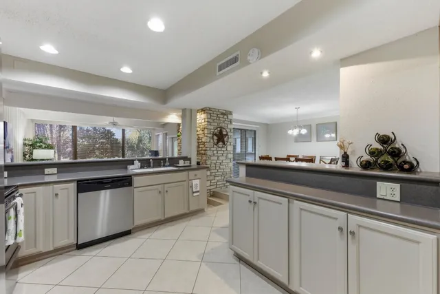 a large white kitchen with granite countertop lots of white cabinets a sink and dishwasher