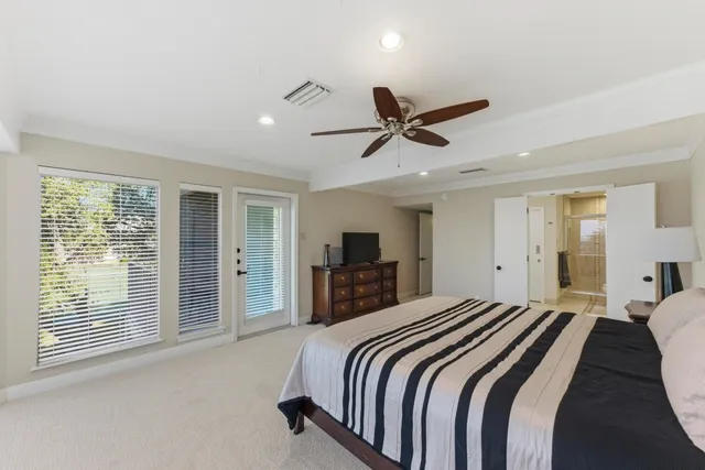 a spacious bedroom with a large bed a flat tv screen and a large window