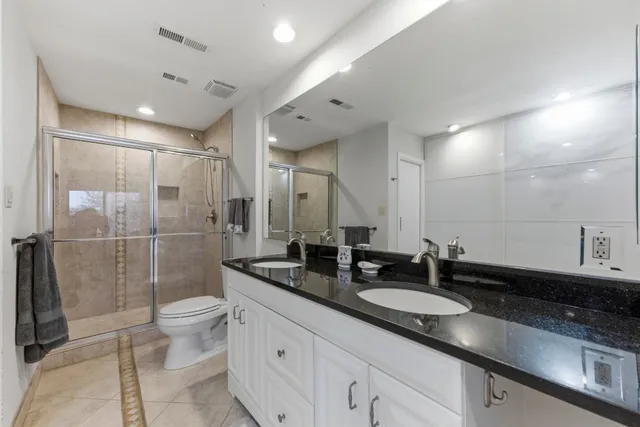 a bathroom with a double vanity sink toilet and shower