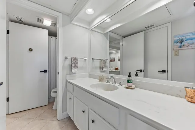 a en suite bathroom with a double vanity sink toilet and a mirror