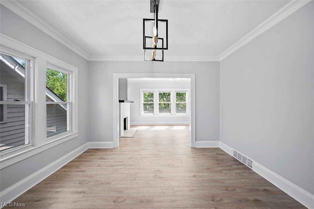2174 Oakdale Road Cleveland, OH 44118 - Photo 25 of 35 Unfurnished room featuring crown molding, an inviting chandelier, a fireplace, and light hardwood flooring
